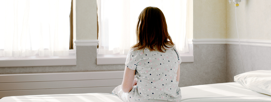 Child sitting on bed staring out window