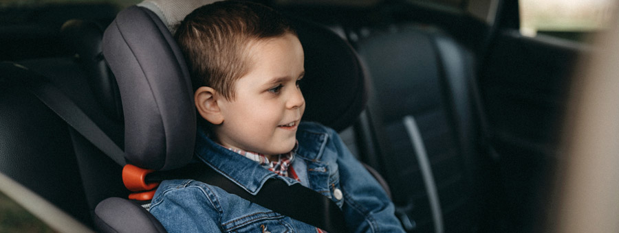 Boy rides in the back seat of car.