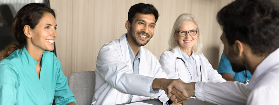 Young doctors shake hands in job interview.
