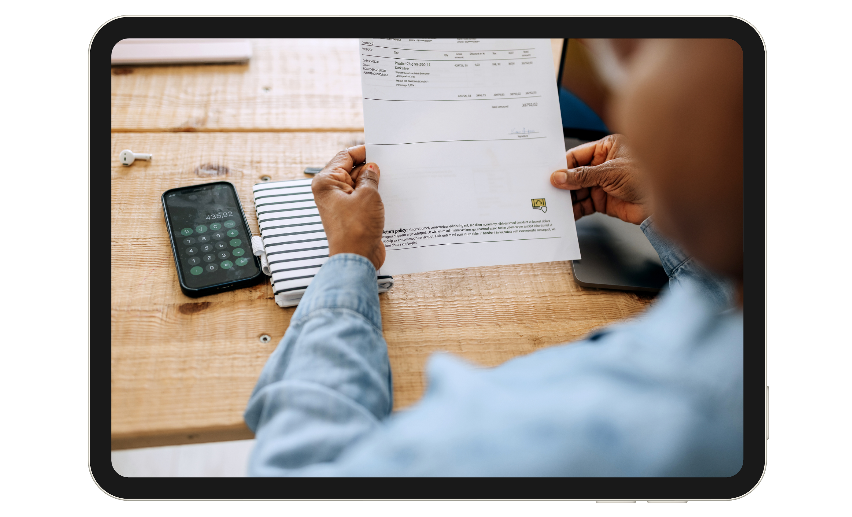 A person looking a piece of paper, with a calculator nearby.