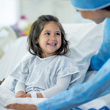 Young girl in hospital bed speaks to doctor.