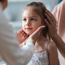 Young girl with mother is examined by pediatrician.